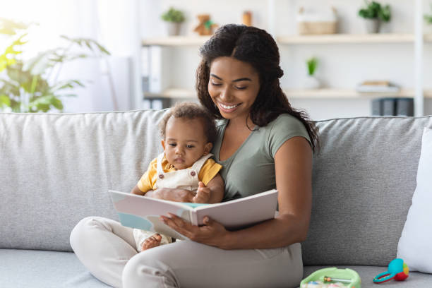 portrait of caring black mom reading book to little baby at home - pregnant animal imagens e fotografias de stock