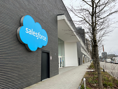 Munich, Bavaria Germany - December 20, 2021: Salesforce internet corporation brick office building with blue cloud logo, windows, and trees in Munich Germany.