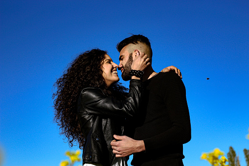 portrait of young smiling couple kissing with blue sky in the background