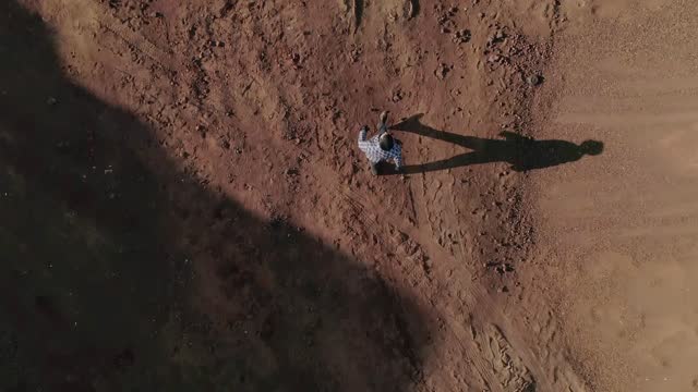 Top view from above . Young man dressed in original costume standing and walking in abandoned land like desert or another planet .  Boy get lost in wasteland . Slow motion . Shot for video clip .