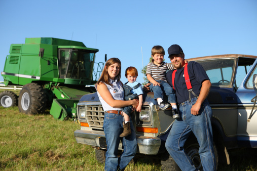 Farm family: mother, father and two sons with truck and combine