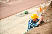 istock Insurance agent or roofer on roof assessing damage to a roof 1369018989