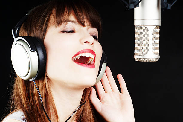 girl singing to the microphone in a studio stock photo