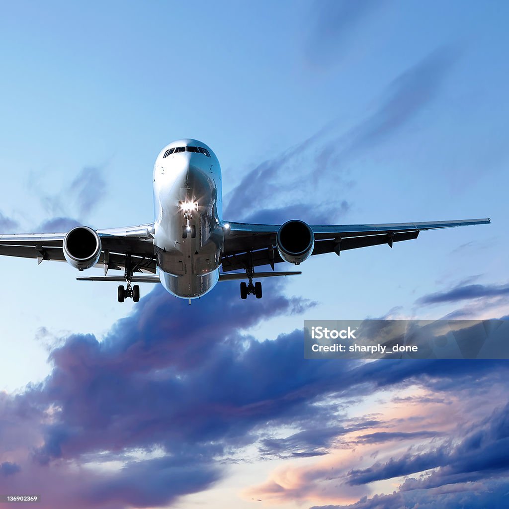 Odrzutowy Samolot pasażerski lądowania o zachodzie słońca - Zbiór zdjęć royalty-free (Samolot transportowy)