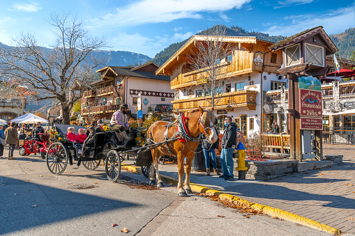 The picturesque Bavarian themed village in the Cascade mountains of Eastern Washington, Leavenworth Washington, with holiday decorations and tourists riding horse drawn carriages through the small town.