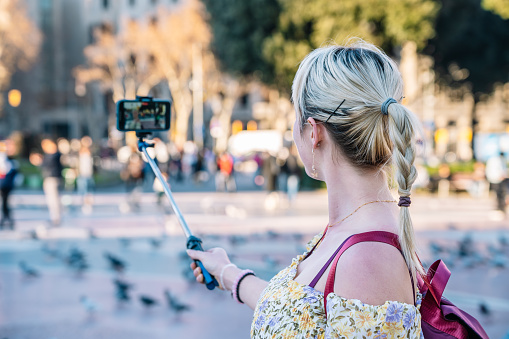 Smiling woman taking selfie on smartphone in center of Barcelona