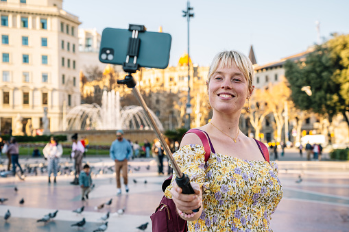 Smiling woman taking selfie on smartphone in park