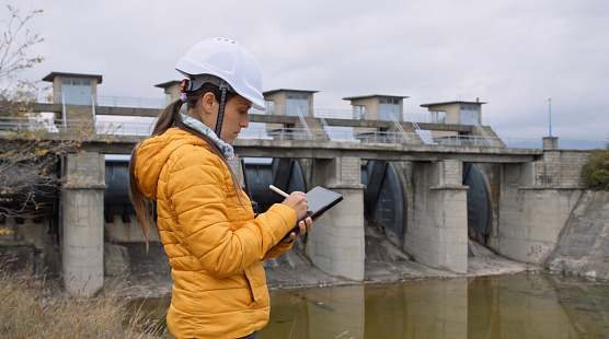 Working day on a water dam with a hydroelectric power plant. Checking the condition of the power equipment, and analysing the data and the results of measurements with a mobile app.