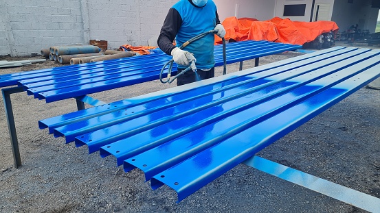 a painter is painting a steel surface blue for a steel building