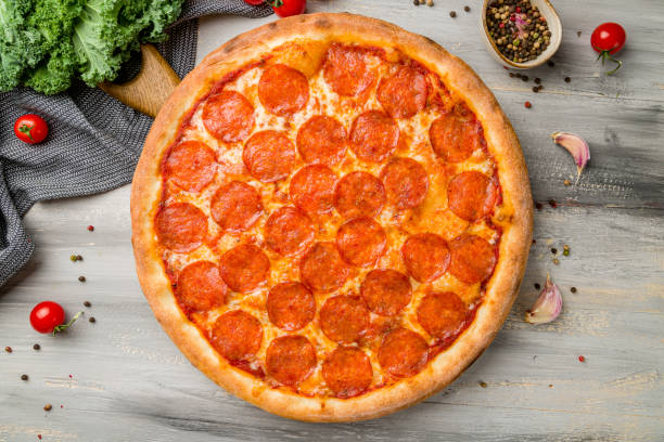 istock Pepperoni pizza on old grey wooden table top view 1369031169