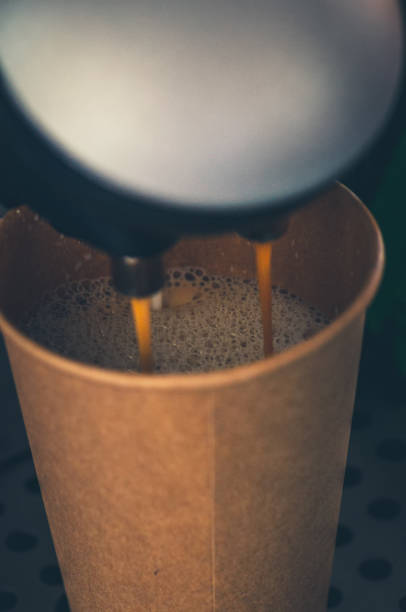 istock Fresh coffee pouring into the paper cup from coffee machine. Selective focus. close up. 1369031193