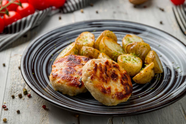 istock Chicken cutlets with baked mini potatoes on grey wooden table macro close up 1369032131