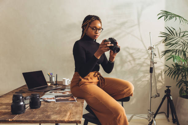 istock Creative photographer holding a dslr camera in her office 1369036499