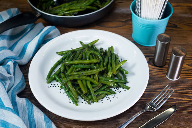 Green beans steamed, drizzled with oil and salt. White plate with a portion of cooked beans. Healthy eating and calorie control. Ideal for vegetarians. stock photo