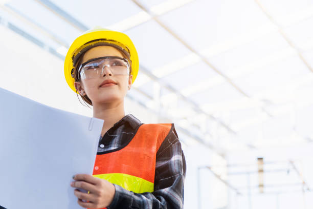istock Asian engineer architect worker woman holding blueprint infrastructure progress at construction site 1369040253