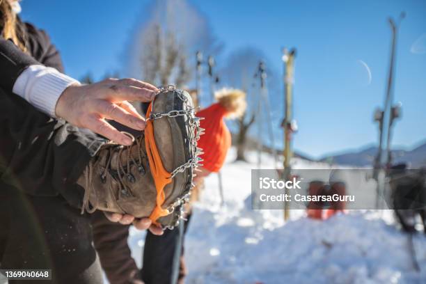 Closeup Of Man Sitting By A Ski Slope With Crampons On Hiking Boots Stock Photo - Download Image Now