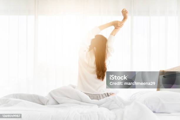 Good Morning New Day Asian Woman Wake Up And Sitting Body Stretch On Bed Beside Window In Bedroom Stock Photo - Download Image Now