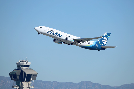 Los Angeles, California, USA - February 06, 2022: Alaska Airlines Boeing 737 Aircraft with ATC Tower Background - Los Angeles International Airport (LAX).