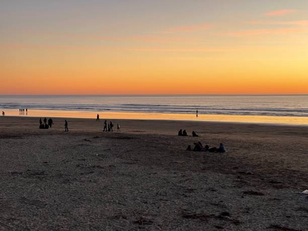 istock People relaxing on the beach at sunset 1369059455