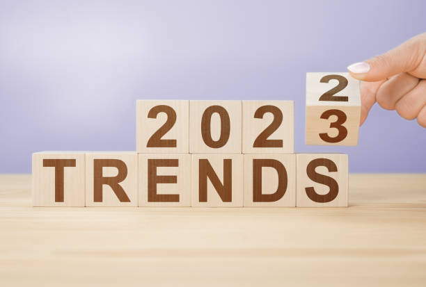 businesswoman turns wooden cube and changes words 2022 to 20223 on very peri color background. trends 2022 2023 word alphabet letters - fashionable stockfoto's en -beelden