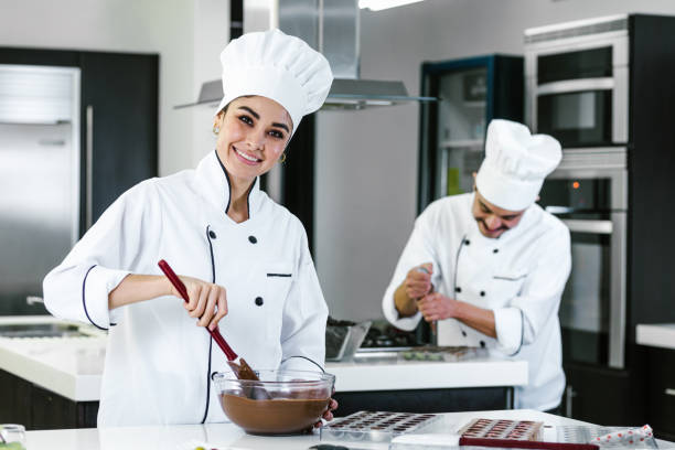 femme chef pâtissière latine portant un uniforme tenant un bol préparant de délicieux chocolats sucrés à la cuisine au mexique amérique latine - pâtissier photos et images de collection