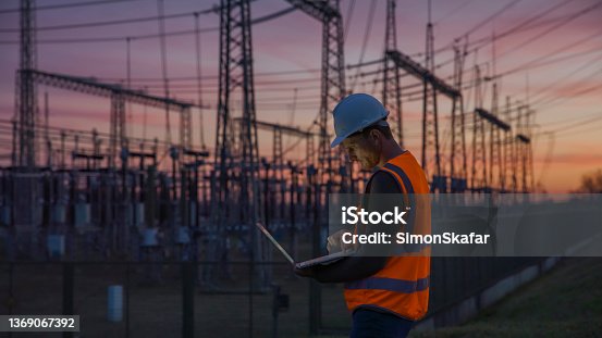 istock Confident male engineer using a laptop in front of electric power station 1369067392