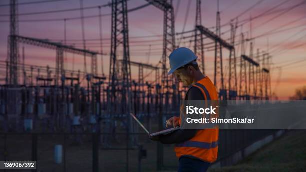 Confident Male Engineer Using A Laptop In Front Of Electric Power Station Stock Photo - Download Image Now