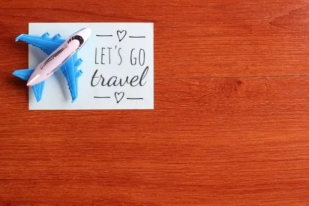 Photo of Toy plane and blue paper with text LET'S GO TRAVEL.