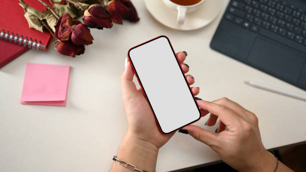 istock Feminine workspace with smartphone in female hands 1369070654