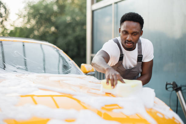 istock Young attractive African man washing his car 1369073825