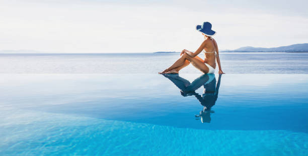 istock Young woman enjoying a sun at infinity pool 1369074171