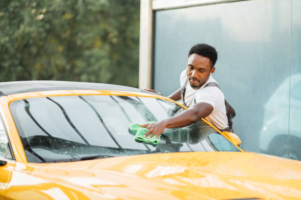 istock Handsome bearded young guy cleaning sport car windscreen 1369074221