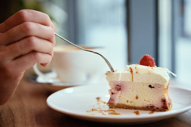 Woman eating rasberry cheesecake and drinks coffee in cafe, breakfast at public place