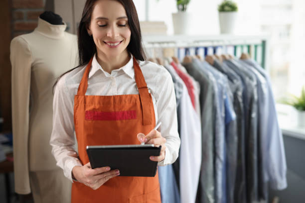 istock Smiling female receptionist holding tablet in dry cleaners 1369074455