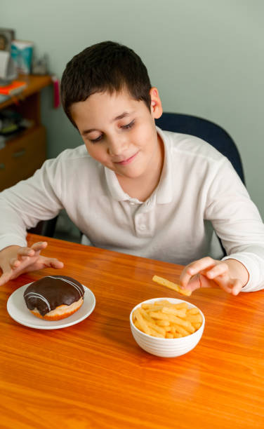 ребенок ест чипсы весело. маленький ребенок ест картофельные чипсы - overweight child little boys diabetes стоковые фото и изображения