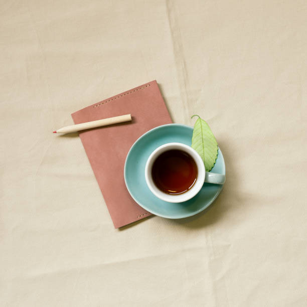 Diary notebook and cup of coffee on beige fabric background. top view, copy space