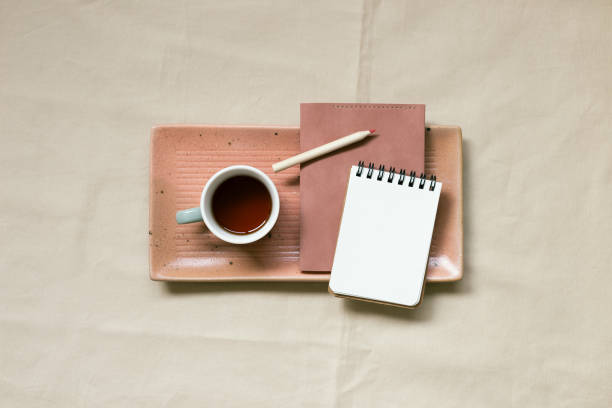 istock Notepad and cup of coffee on beige fabric background. top view, copy space 1369076574