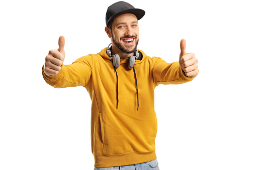 Smiling young man with headphones showing both thumbs up isolated on white background