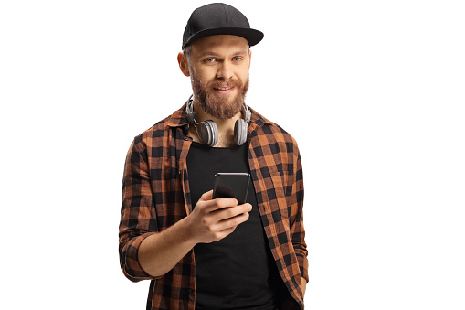 Trendy guy with headphones holding a smartphone and looking at camera isolated on white background