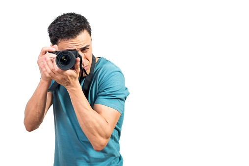 Focused male photographer taking picture on photo camera on white isolated background in studio