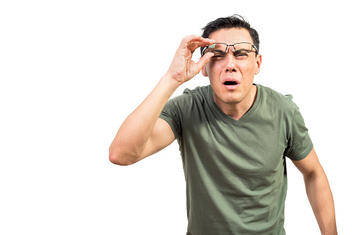 Smart man with bad eyesight lifting glasses and looking at camera while standing against white background