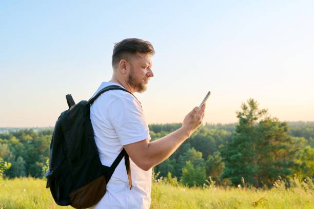 istock Middle aged bearded man with smartphone backpack on hike, making video call 1369079062