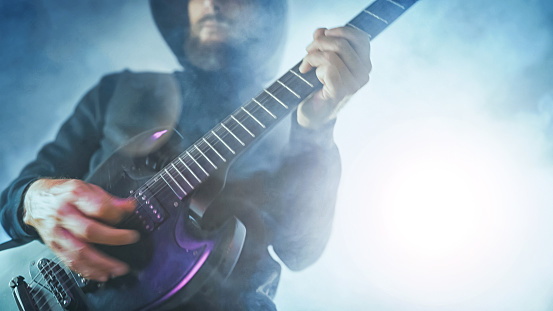 Heavy metal rock guitarist playing guitar in a live show with stage lights
