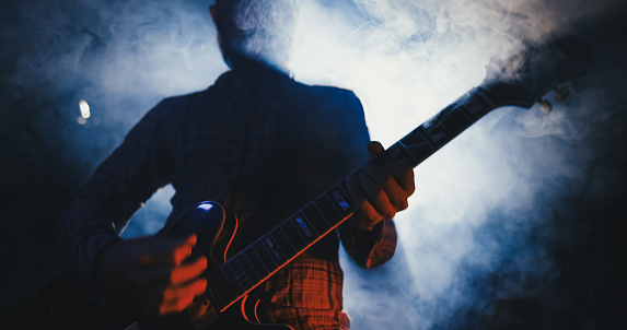 Rock guitarist playing guitar in a live show, lights and smoke
