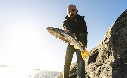 Man spinning fishing in the sea with a rod, from the rocks