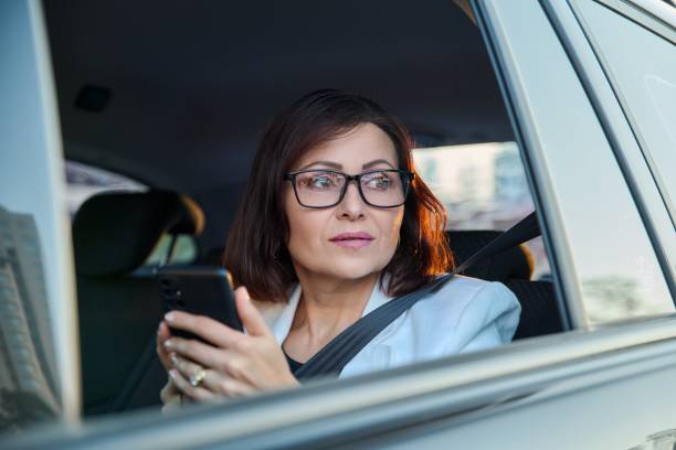 ritratto di donna d'affari di mezza età in auto sul sedile posteriore del passeggero. - taxi travel business women foto e immagini stock