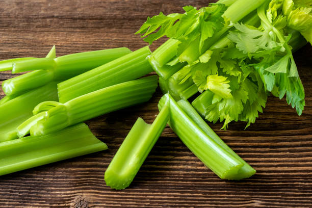 Cut celery sticks and leaves on wooden table Cut celery sticks and leaves on wooden table celery stock pictures, royalty-free photos & images