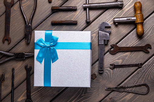 A gift on the background of Fathers ' Day, a postcard on a wooden background with repair tools and a gift box