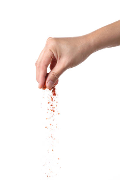 istock Hand sprinkling cayenne pepper on white background 1369083689