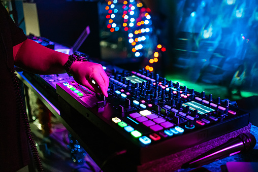 male DJ mixes electronic music on a professional music controller in a nightclub at a party